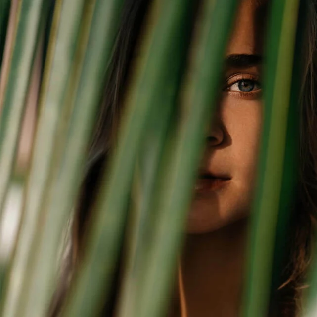 Close-up portrait behind green leaves